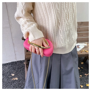 Detail of rose pink woven clutch bag with gold round metal handle and chain strap