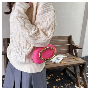 Close-up of rose pink woven leather crossbody bag with oversized gold C-buckle clasp