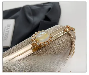 Detail of the golden evening bag featuring a sun flower clasp with crystals and marble inlay