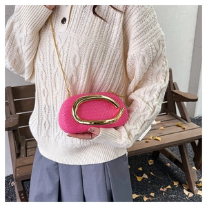 Detail of rose pink woven clutch featuring a large gold C-clasp and metal chain strap