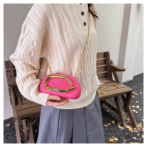 Close-up of pink woven box bag with gold U-shaped hardware on a model outfit