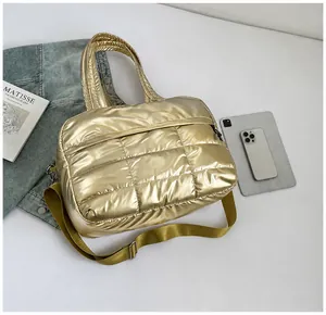 Vista de detalle del bolso tote acolchado dorado con textura metálica y correa extraíble