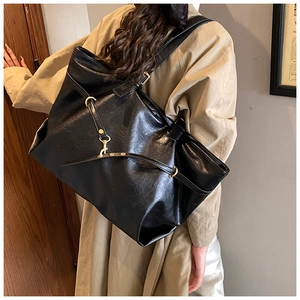 Macro detail of black faux leather tote with grain texture and gold metal accents