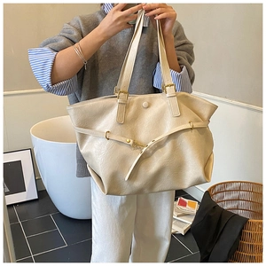 Detail view of cream tote bag with natural leather texture and gold metal hardware