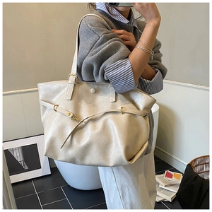 Detail of a large cream tote bag showing vintage leather texture and gold buckles