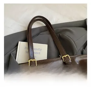 Close-up of vintage coffee brown tote bag with gold metal buckles on suit background