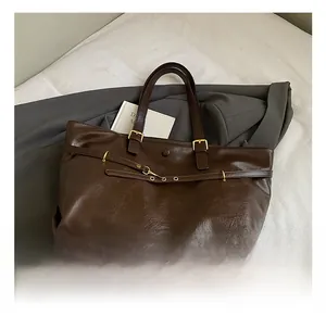 Detailed macro of vintage brown tote bag with oily leather texture and golden buckles