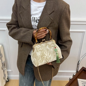 Retro velvet handbag with bamboo handle, gold chain and tassel on beige bamboo leaf fabric