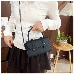 Detail of black contrast stitch crossbody bag with metal chain strap and top handle