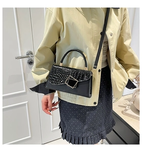 Fashionable black crocodile pattern handbag with gold clasp on chic beige office outfit