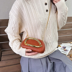 Retro woven caramel clutch bag with gold U-buckle and chain strap shown with a model