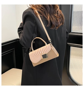 Detail of beige faux crocodile texture bag with gold buckle on black blazer