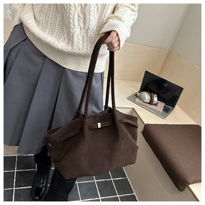 Dettaglio della borsa tote in pelle scamosciata opaca marrone con manici sottili e fibbia d'oro