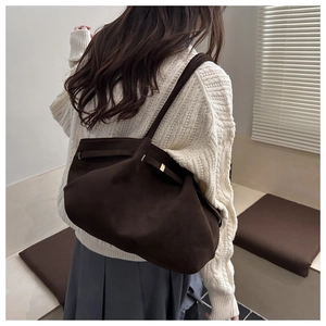 Grande borsa tote in pelle scamosciata marrone indossata da una modella in un interno