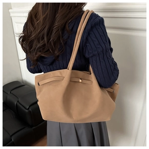 Detail of a large camel suede tote bag with side straps and metal buckles for women