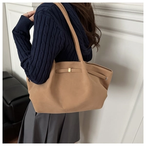 Close-up of khaki tote bag with gold buckle on shoulder of model in casual attire