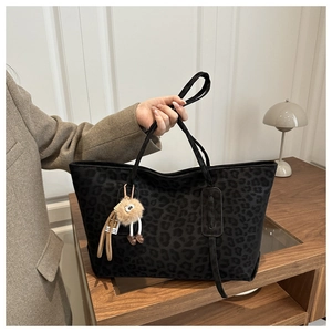 Detail of leopard print tote bag with plush charm in a cozy minimalist interior setting