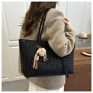 Detail of black leopard print tote bag with a unique plush charm and long shoulder straps