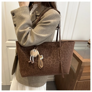 Detail of large leopard print tote bag in dark brown with plush charm and leather straps