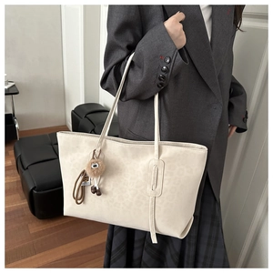 Close-up of beige leopard print tote bag with plush charm and long strap detail