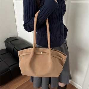 Elegant camel suede bucket tote bag with gold hardware shown as a shoulder bag