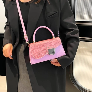 Rosa Umhängetasche mit Krokodilstruktur und Schnalle getragen auf einem schwarzen Blazer