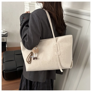 Détail d'un sac cabas à imprimé léopard avec pendentif mouton porté à l'épaule