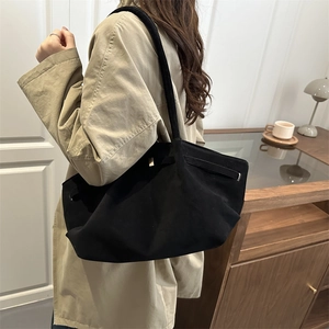 Minimalist black suede tote bag with metal buckle shown in a lifestyle home setting