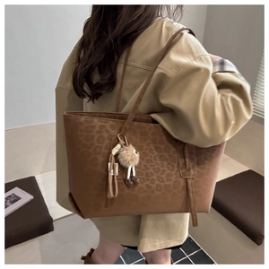 Détail du sac cabas imprimé léopard avec breloque en peluche porté à l'épaule en situation