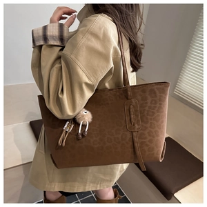 Détail d'un sac cabas marron à motif léopard avec un pendentif en peluche mignon
