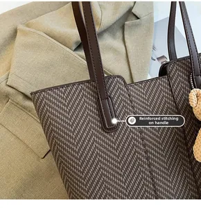 Close-up of chevron tote bag with reinforced stitching and plush bear charm detail
