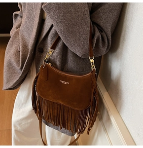 Detailed view of brown suede fringe bag with bohemian tassels and gold metal accents