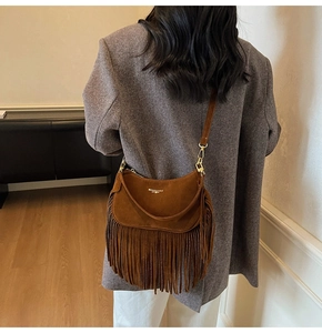 Detailed view of the vintage brown suede crossbody bag featuring long fringe tassels and logo