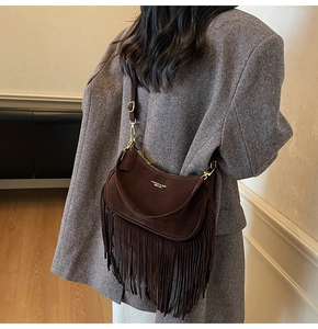 Close-up of brown suede crossbody bag with long fringe and vintage gold hardware