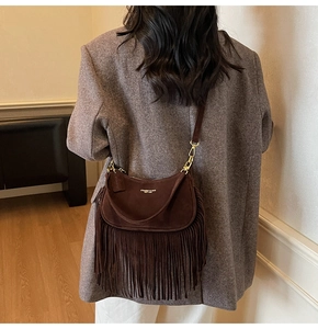 Detail of dark brown suede crossbody bag with long tassels and gold metal hardware