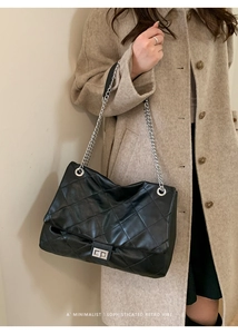 Close-up of black quilted leather tote bag with silver square lock and metal chain strap