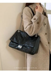 Detail of black quilted leather shoulder bag with silver chain strap and metal clasp
