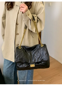 Detail of black quilted leather tote bag with gold chain strap and turn-lock closure