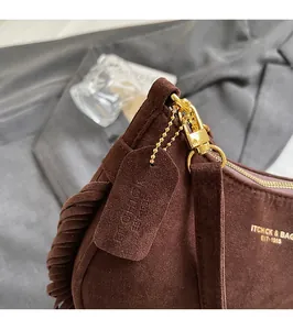 Detailed macro of brown suede shoulder bag featuring fringe tassel and gold hardware