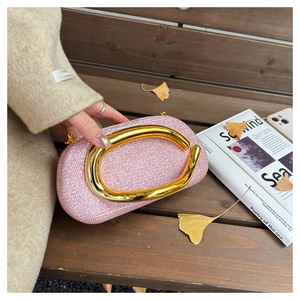 Pink sequin evening clutch bag with gold horseshoe handle on wooden outdoor background