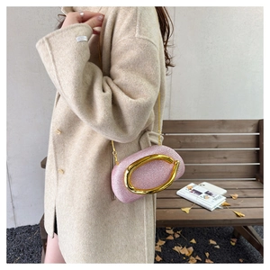 Detail of pink glitter clutch with a large gold C-clasp and metallic chain strap