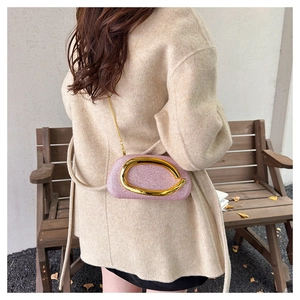 Chic pink sequin evening bag with gold oval buckle shown on a stylish wool coat