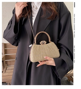 Detail of golden pleated clutch with rhinestone handle and metal clasp for women
