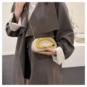 Detail of champagne gold sequin clutch bag with metallic ring handle worn with a long coat