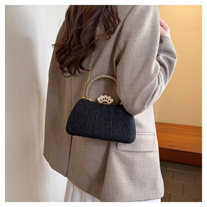 Close-up of black glitter evening bag with gold crown clasp and metallic chain strap
