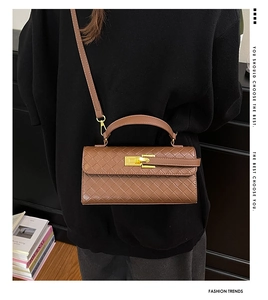 Borsa a mano marrone intrecciata con chiusura dorata a scatto indossata da modella