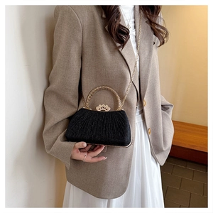 Detail of black pleated fabric clutch with golden crown buckle and diamond accents