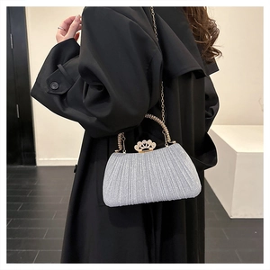 Detail of silver glitter evening bag with crown clasp and pleated metallic texture