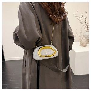 Detail of silver sequin evening clutch bag with gold metal buckle on a brown trench coat