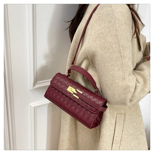 Dettaglio di borsa in pelle intrecciata bordeaux con fibbia dorata portata da modella